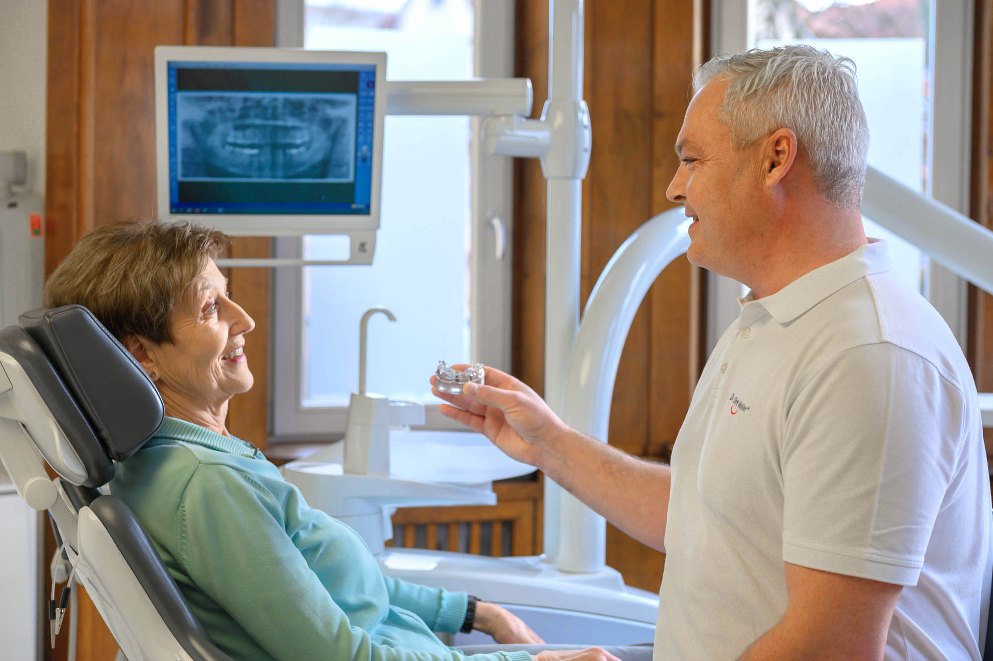 Zahnarzt Meller zeigt Frau Zahnmodell von Zahnimplantat Meller_Zahngesundheit_Implantologie_Z20_0182.jpg